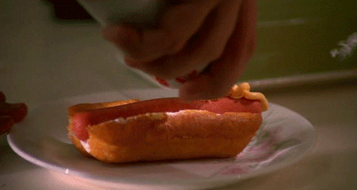 A wiener in a Twinkie is being topped with spray cheese